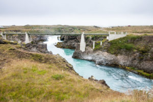 Die alte Brücke über den Skjálfandafljót, von der neuen Brücke aus gesehen. Im Hinntergrund ist die Gischt des Goðafoss zu sehen